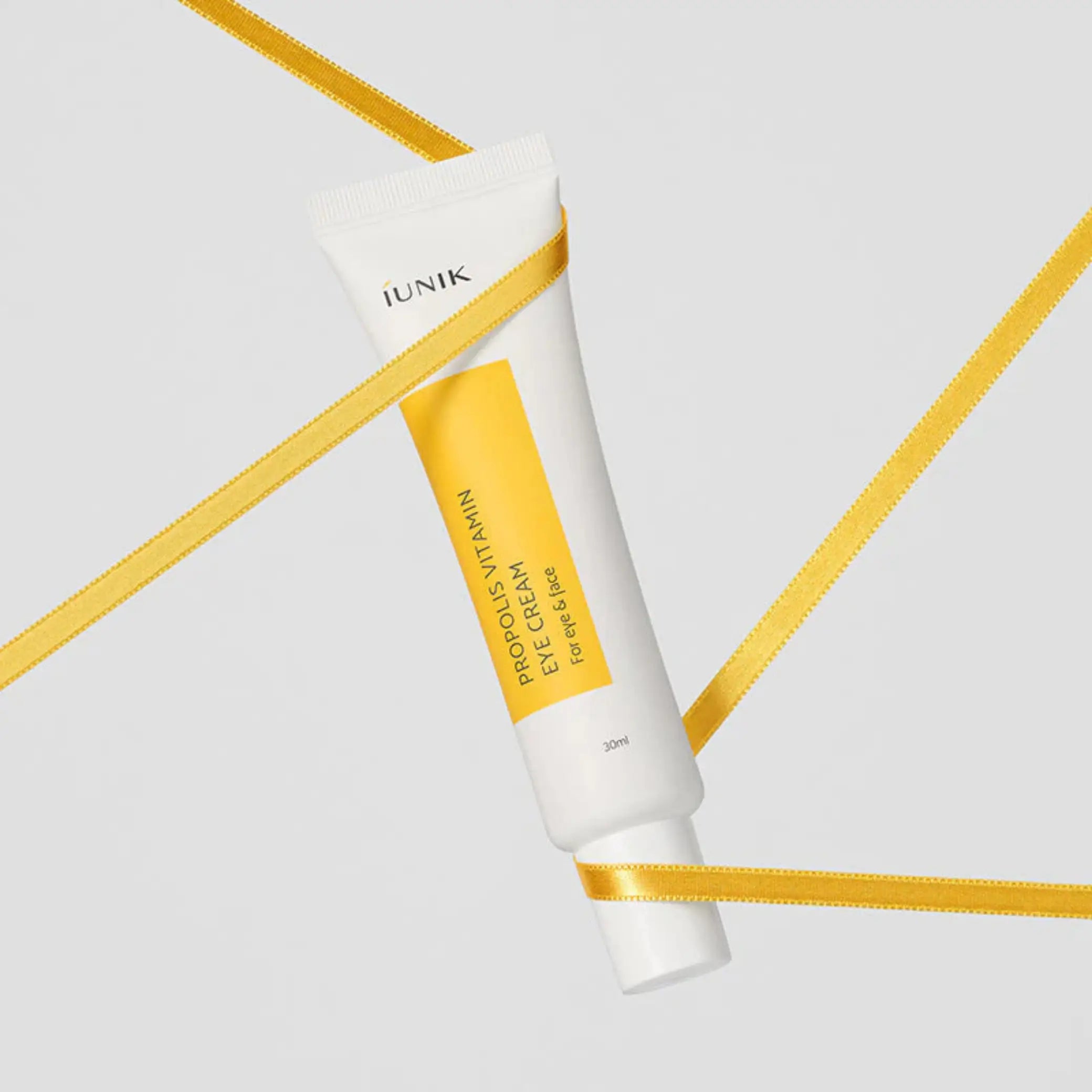 Propolis Vitamin Eye Cream da iUNIK tubo com fita dourada em diagonal em fundo branco